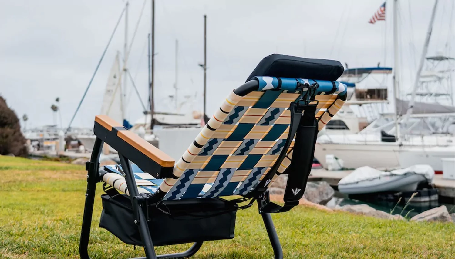 Lounge chair on grassy area near a marina with boats in the background.
