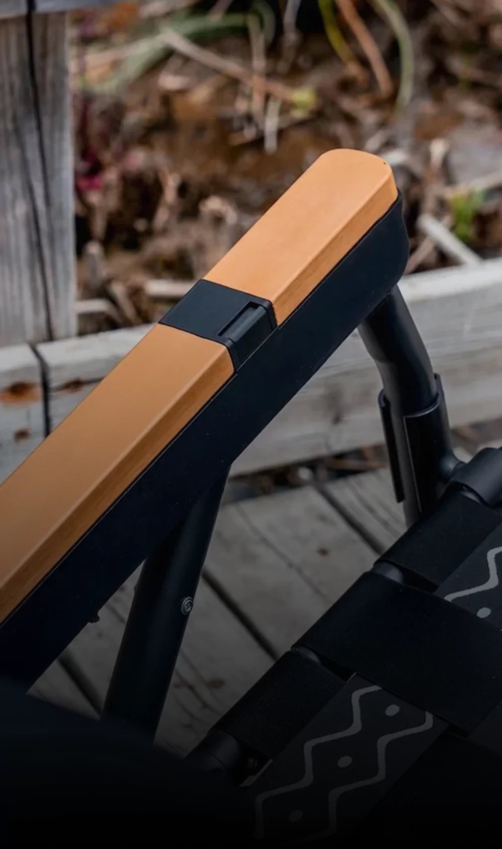 Close-up of a wooden armrest on a black outdoor chair.