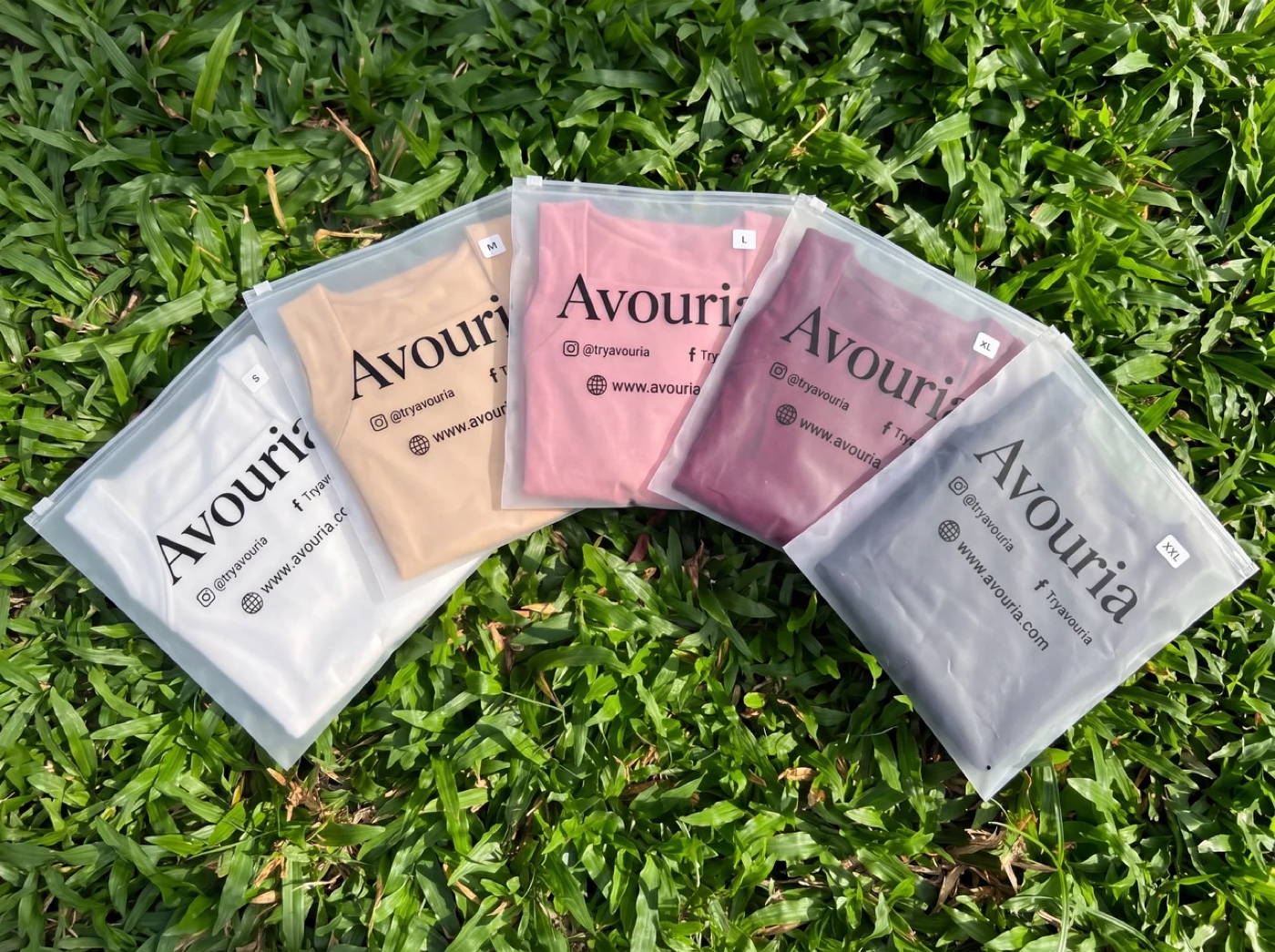 Eight Avouria zip bags fanned out on grass, each holding a tank in a different color