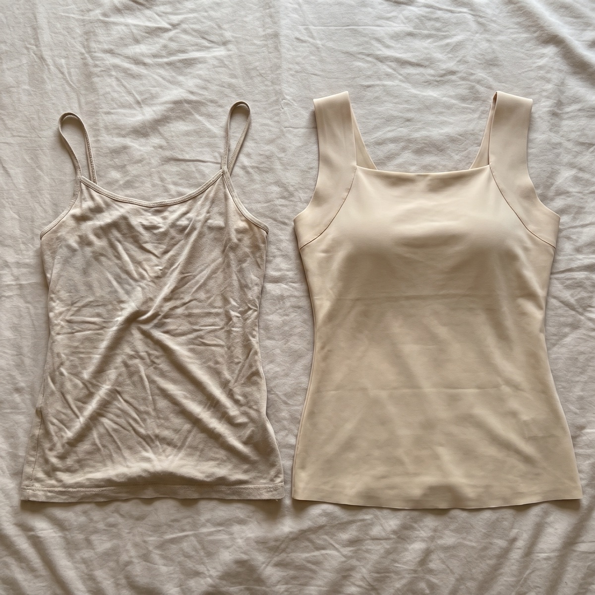 Flat lay of a thin spaghetti-strap camisole next to the structured tank with built-in cups