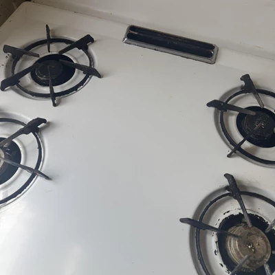 White stovetop with four black gas burners.