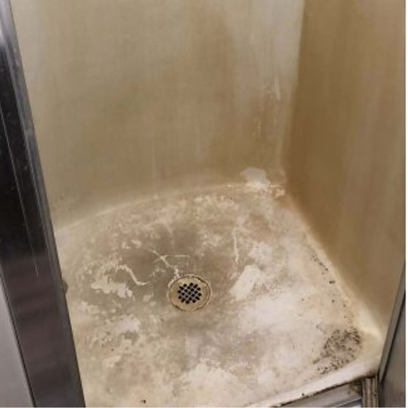 Dirty shower floor with visible stains and drain.