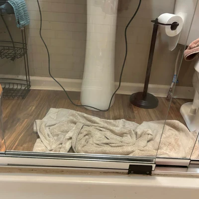 Bathroom with a towel on the floor and a glass shower door.