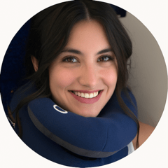 Person smiling with a travel neck pillow.