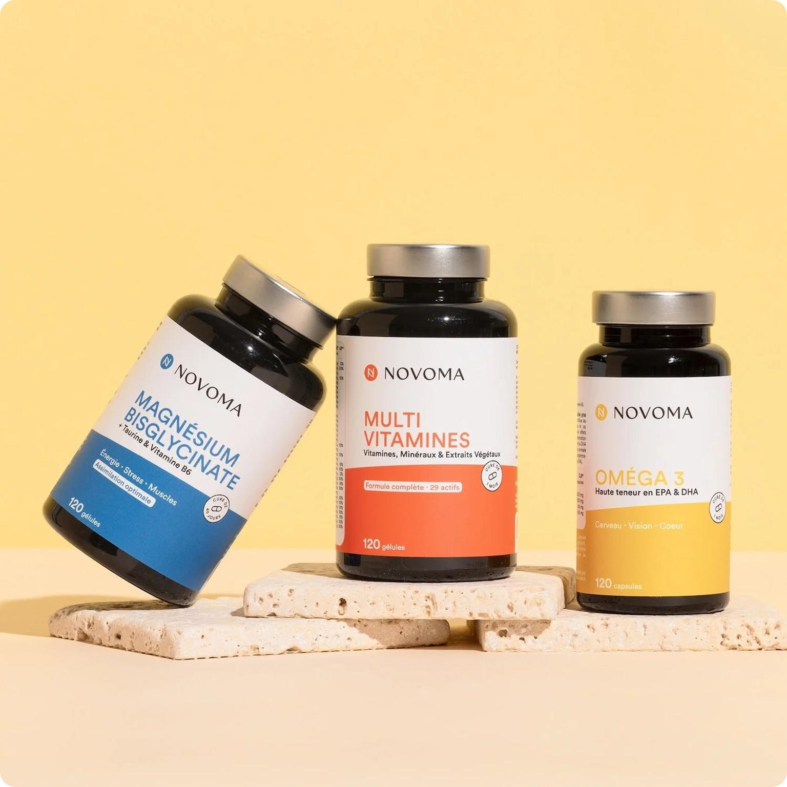 Three bottles of Novoma brand supplements displayed on stone tiles against a yellow background.