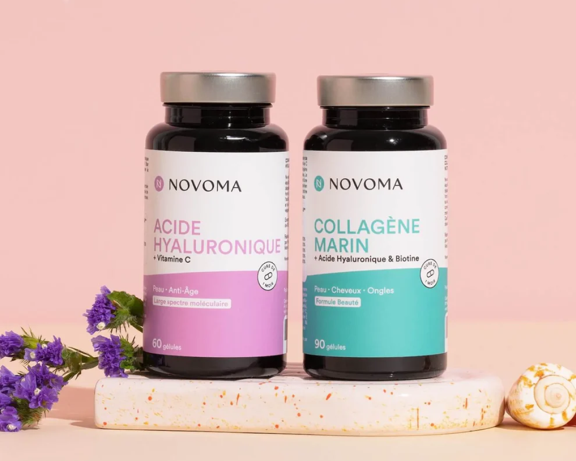 Two bottles of Novoma supplements, Hyaluronic Acid and Marine Collagen, styled with flowers and a seashell.