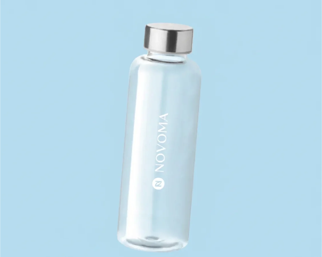 A clear water bottle with a silver cap and the Novoma logo against a light blue background.