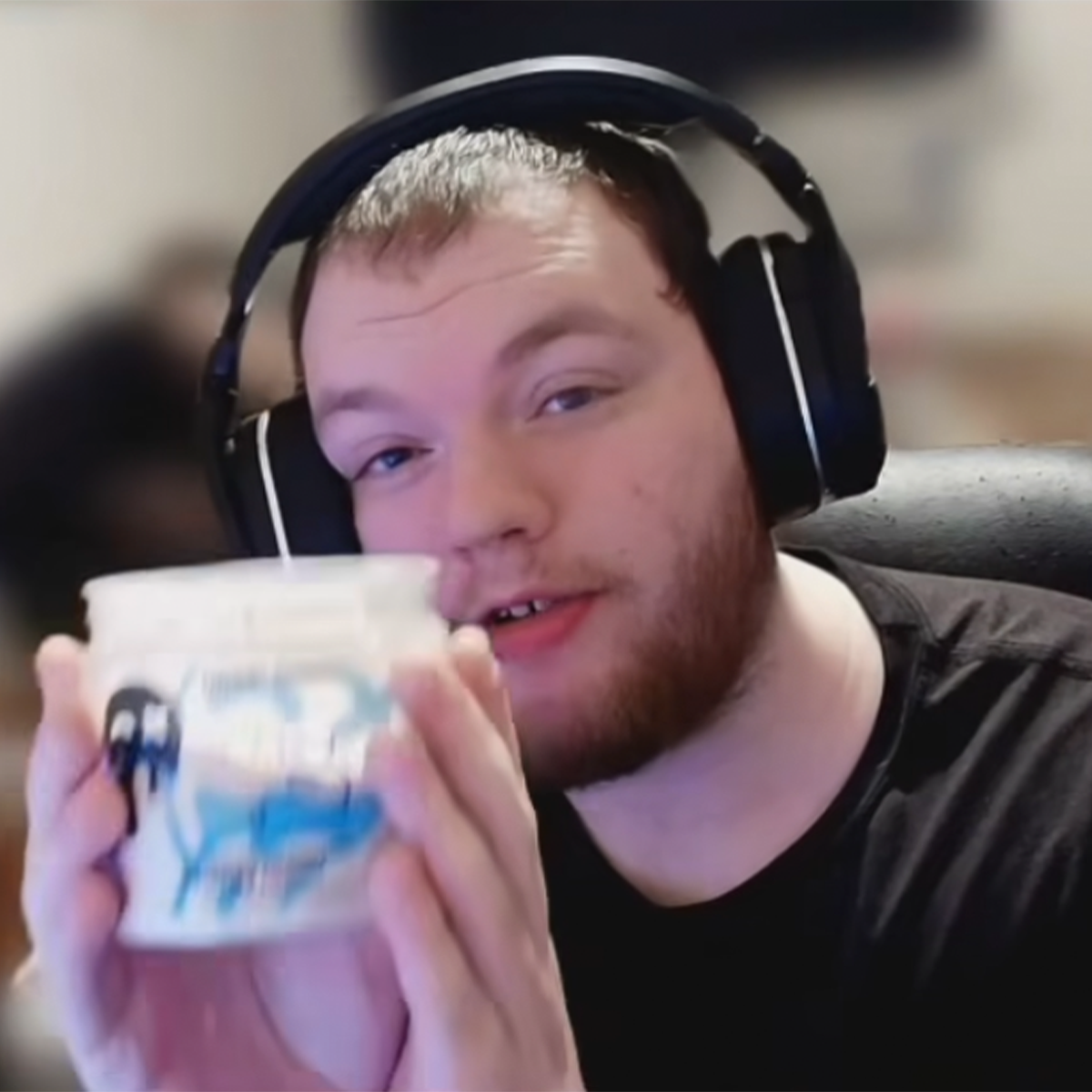 Person wearing headphones holding a container with a blue design.