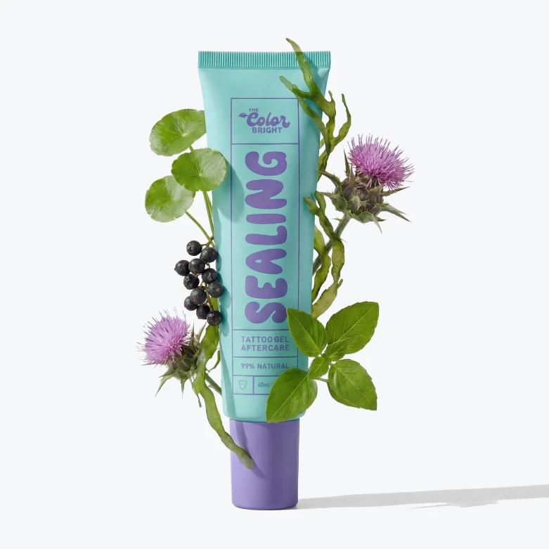 A light blue tube of 'Sealing Tattoo Gel Aftercare' is wrapped in various plants, berries, and flowers.