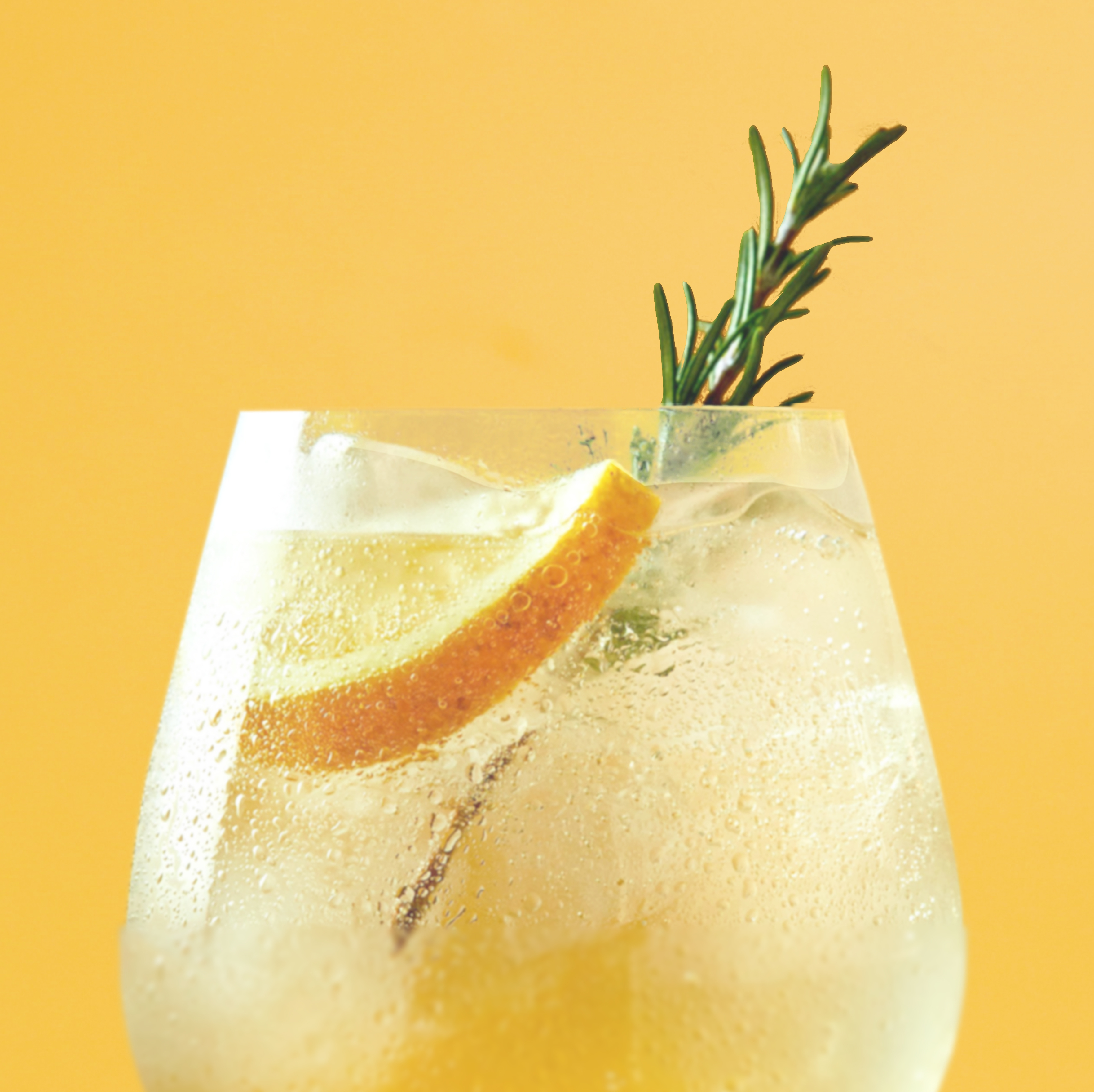 Refreshing cocktail with orange slice and rosemary against a yellow background.