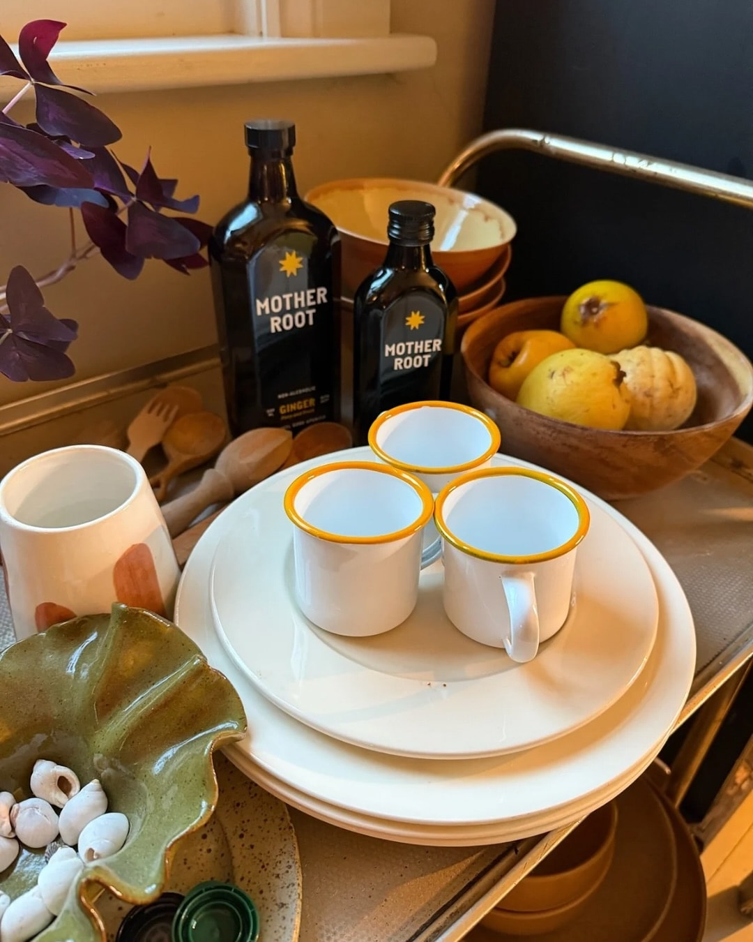Kitchen items including plates, cups, bottles, and fruit on a countertop.