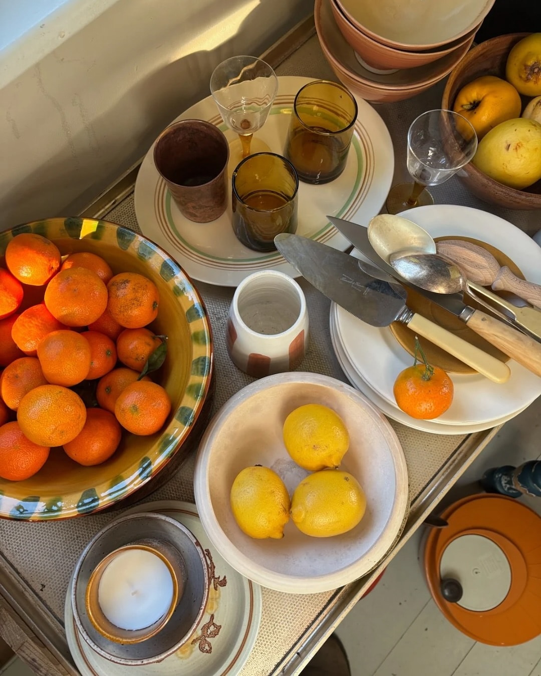Assorted kitchenware and fruits, including oranges and lemons, on a table.