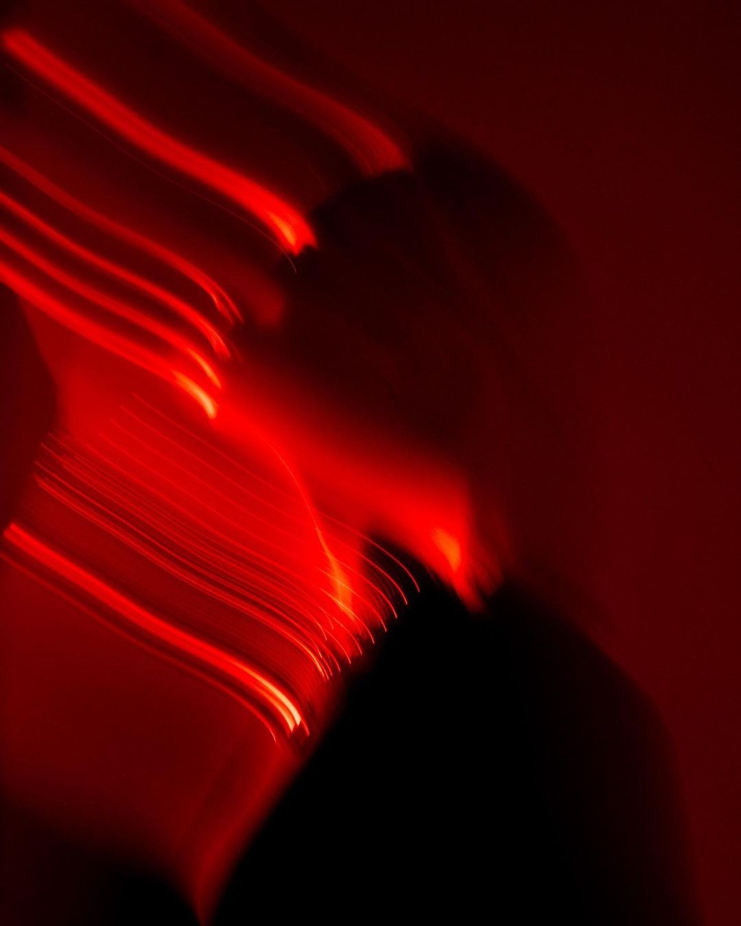 Abstract red light trails against a dark background.