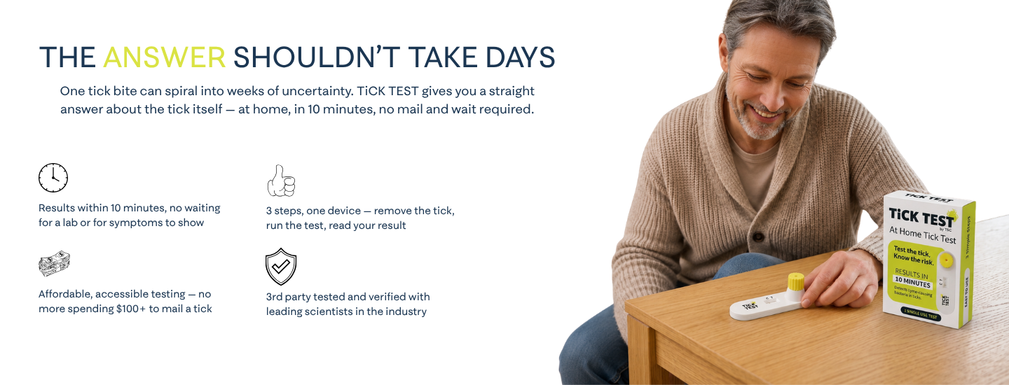 A smiling man sits at a table with an At Home Tick Test kit.