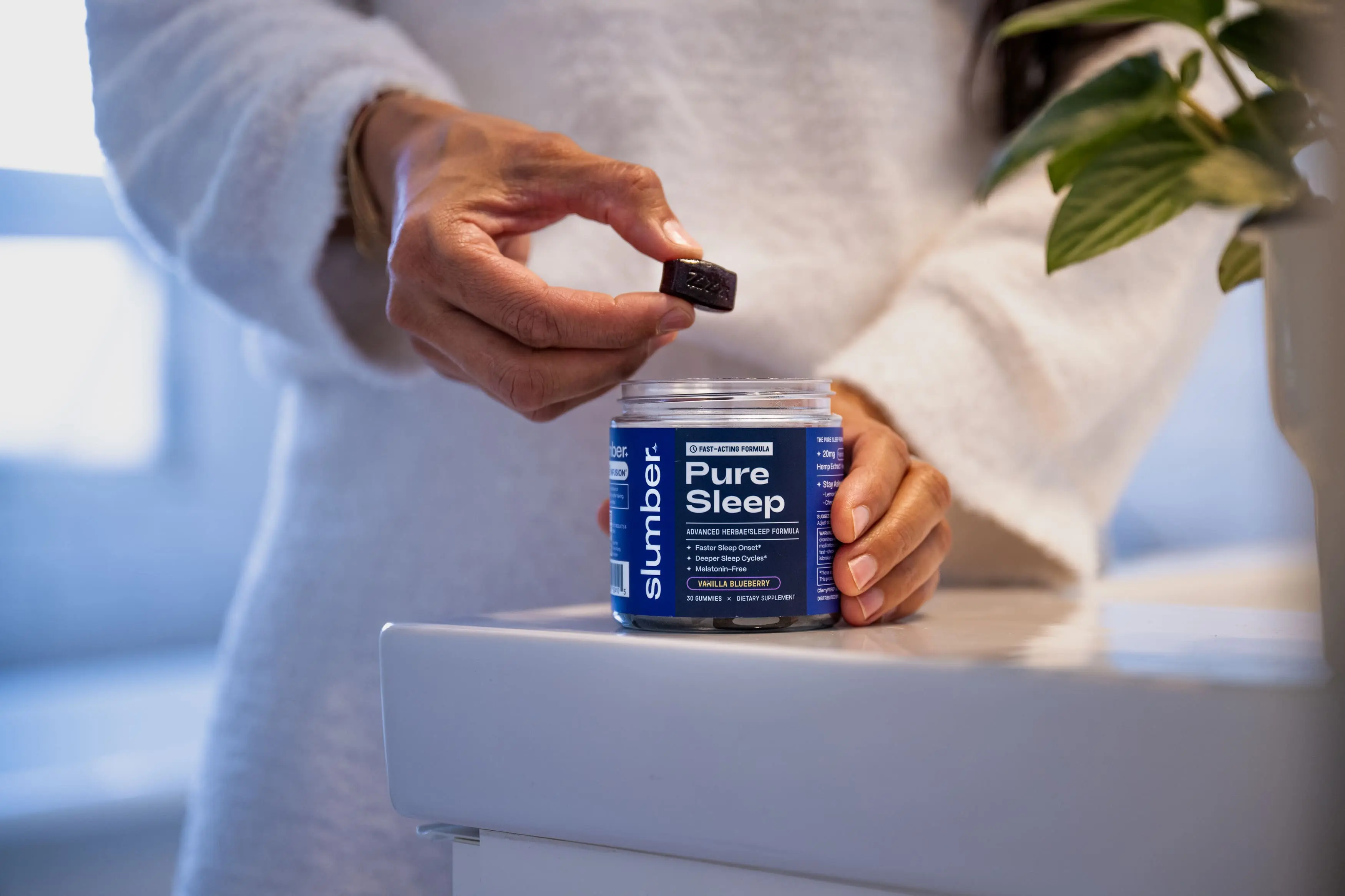 Person holding a gummy above a jar labeled 'Pure Sleep'.