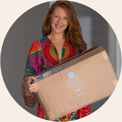 Person holding a large cardboard box with 'Seatopia' logo.