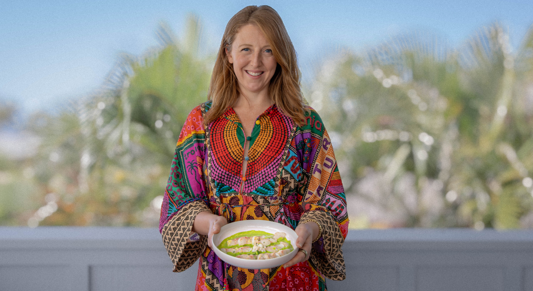 Woman in colorful dress holding a bowl of food outdoors.
