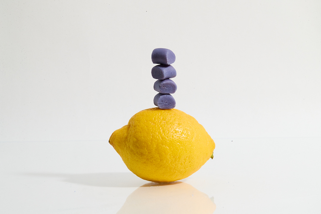 A lemon with four purple stones stacked on top.