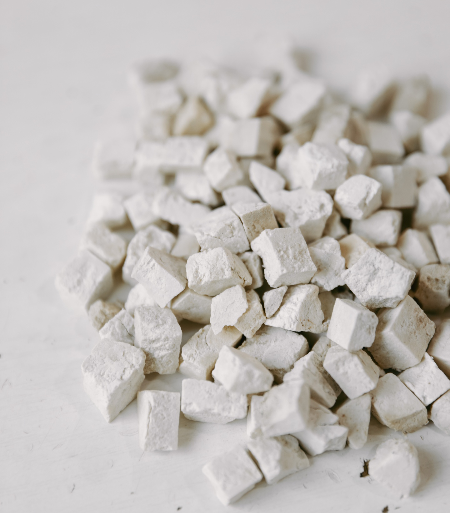 Pile of small, white, irregularly shaped stones on a white surface.