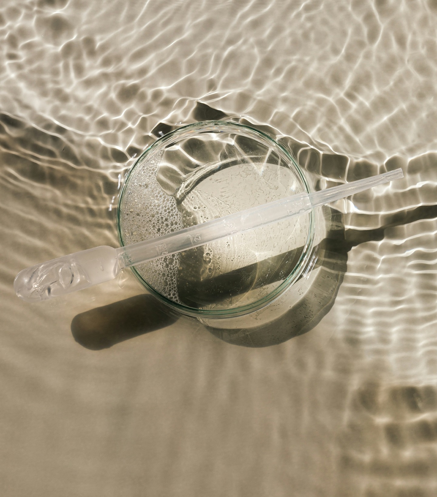 Glass dish with liquid and pipette on rippled surface.