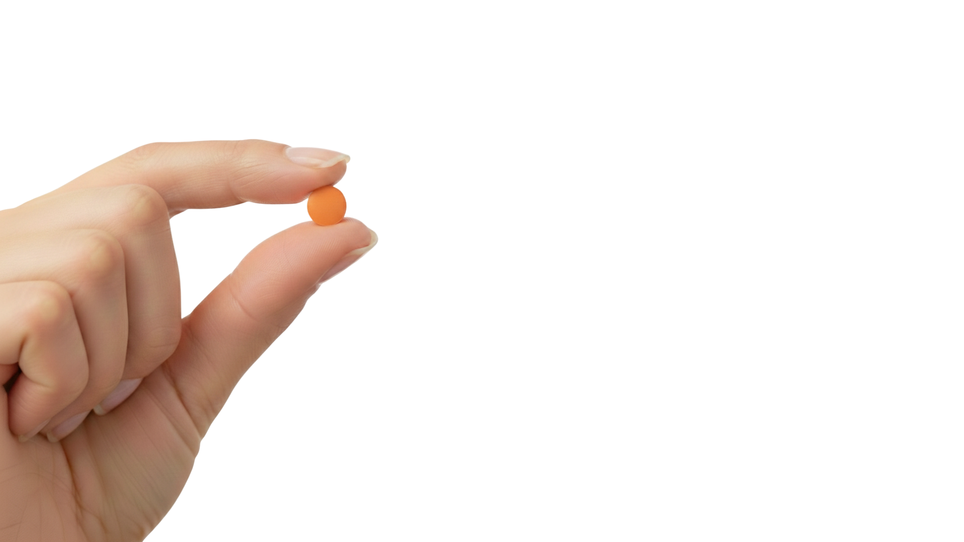 A person's hand holds a small, round, orange pill between their thumb and forefinger on a white background.