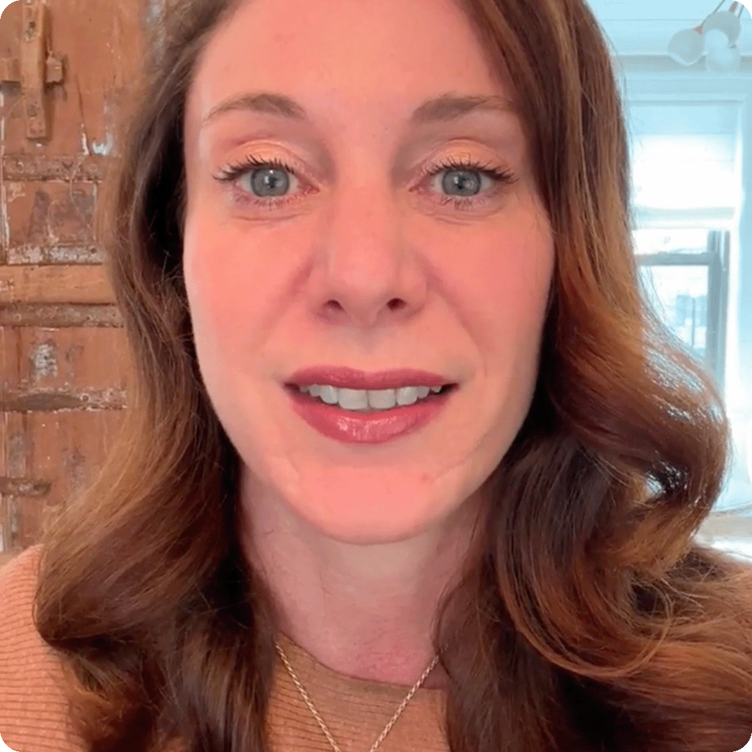 A close-up photo of a smiling woman with long, auburn hair looking directly at the camera.