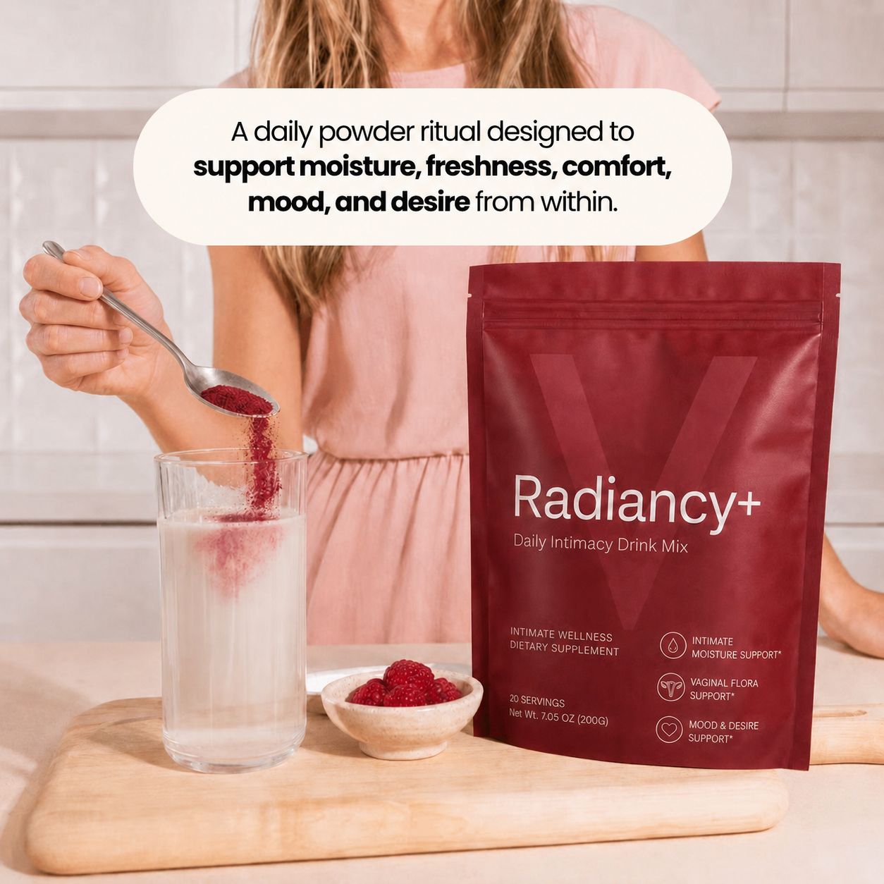 A woman pours a spoonful of red Radiancy+ powder into a glass of water on a cutting board.
