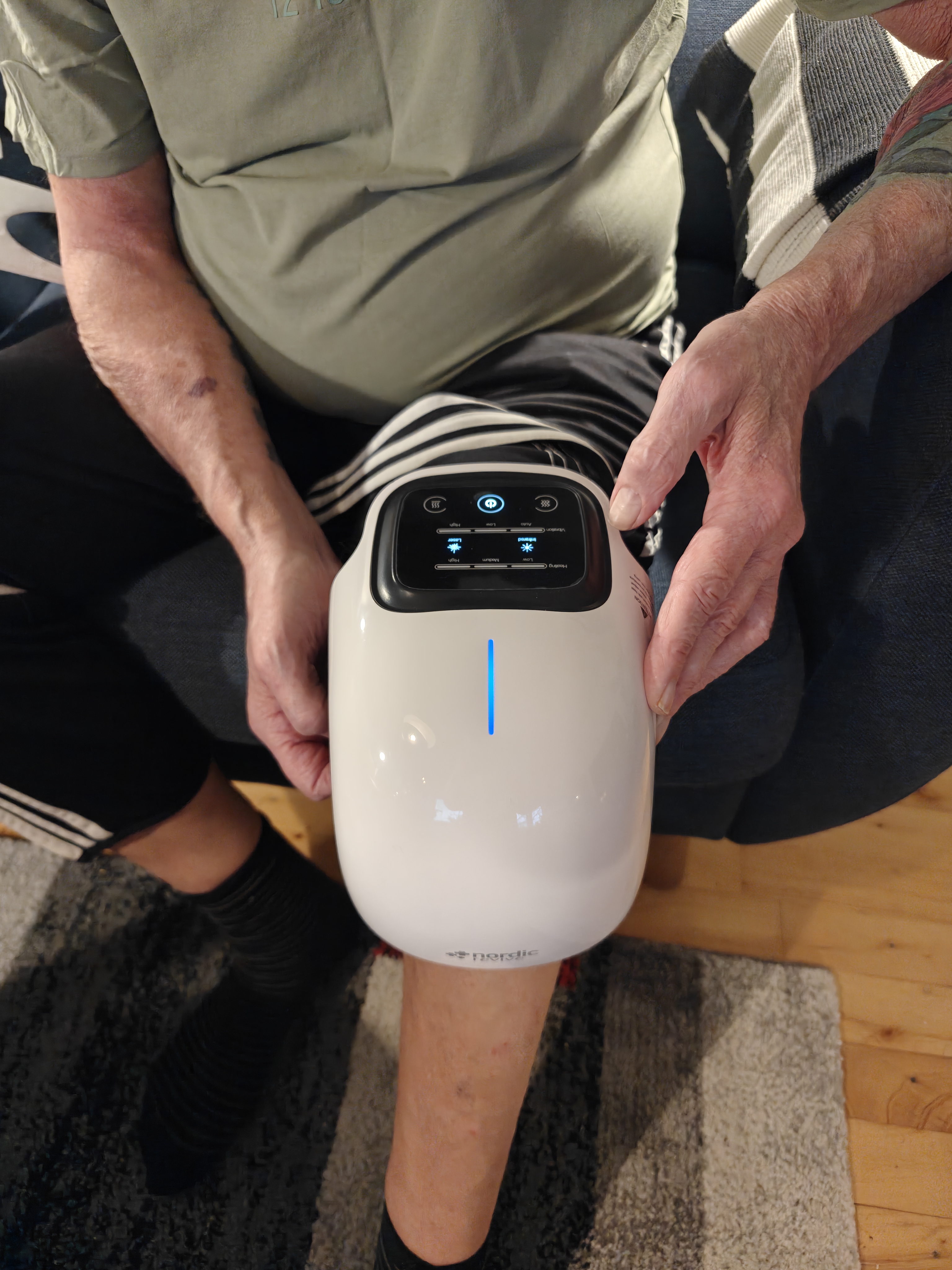 Person holding a white electronic device on their knee.