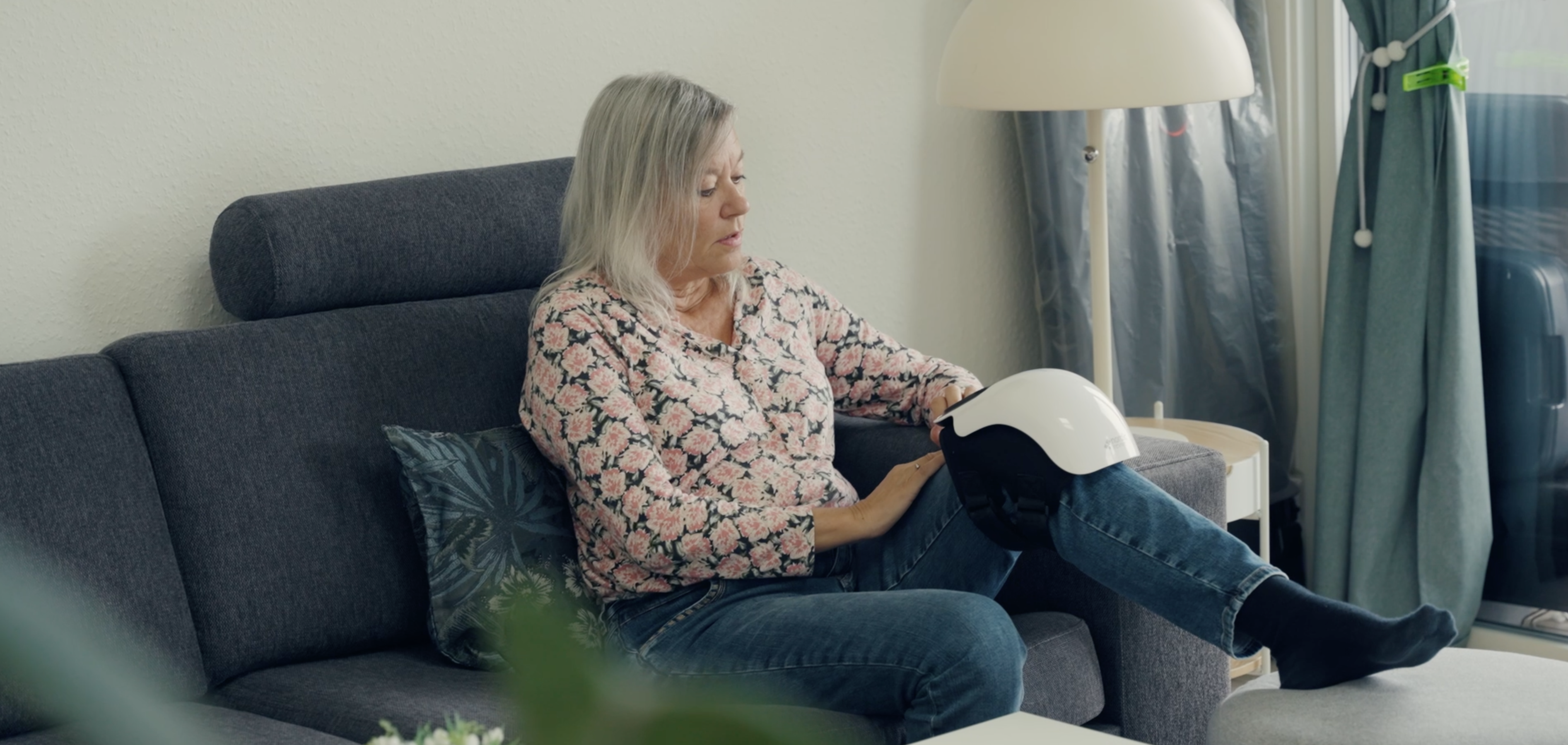 Person sitting on a couch holding a white helmet-like object.