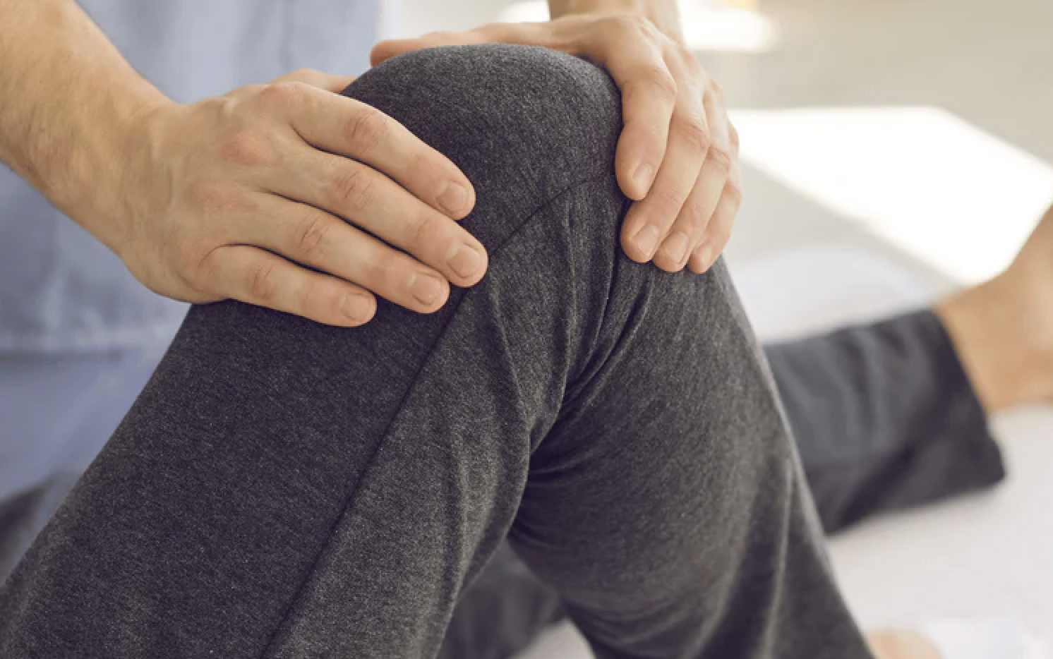 Person's hands on a bent knee wearing dark pants.