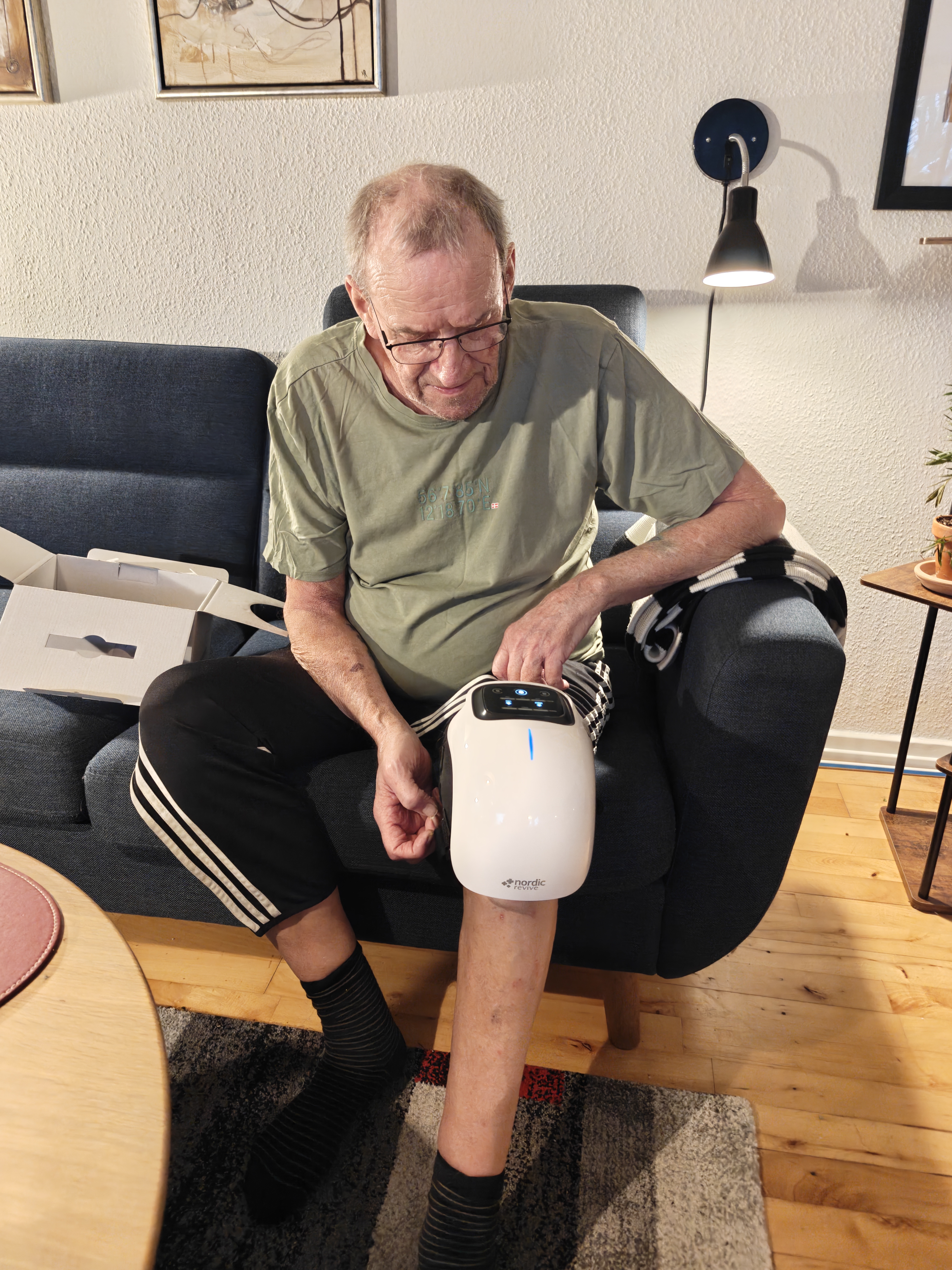 Person sitting on a couch using a leg massager device.