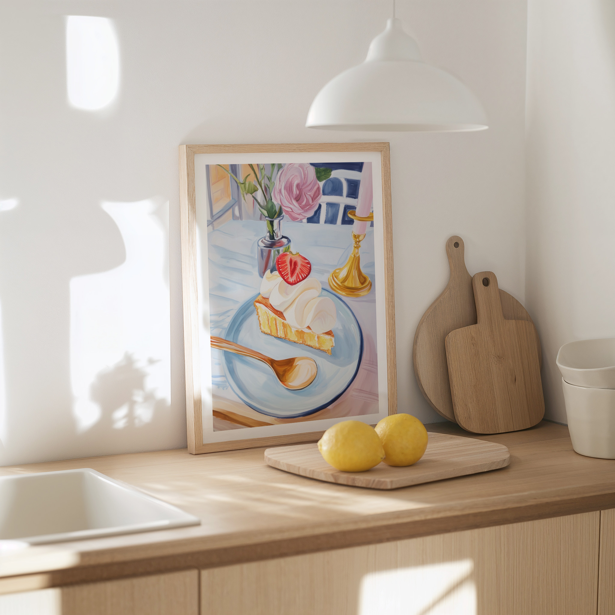 Framed painting of dessert on a kitchen counter with lemons and cutting boards.