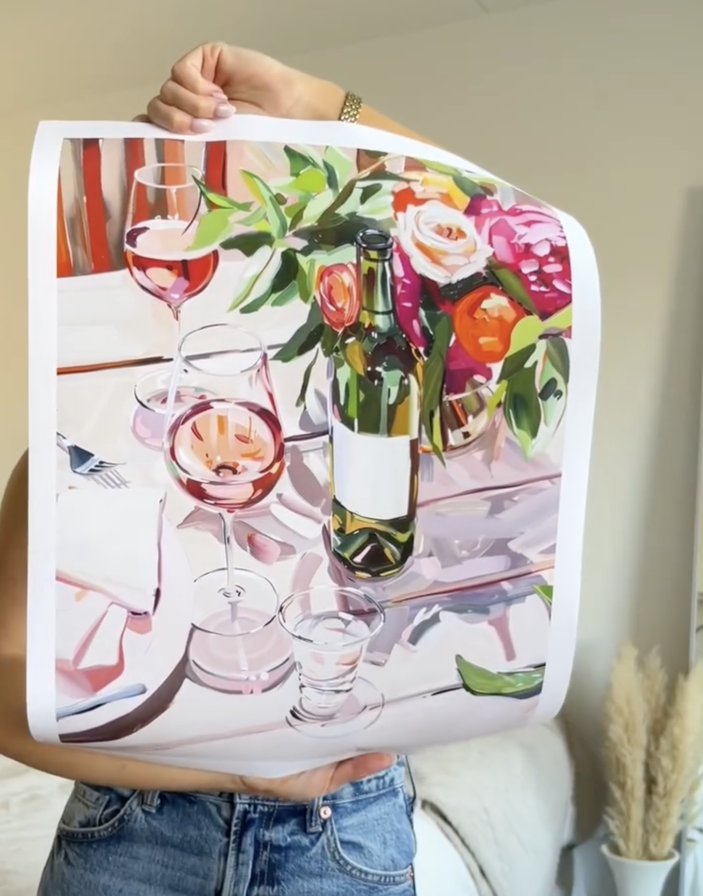 Person holding a colorful painting of wine glasses and flowers.