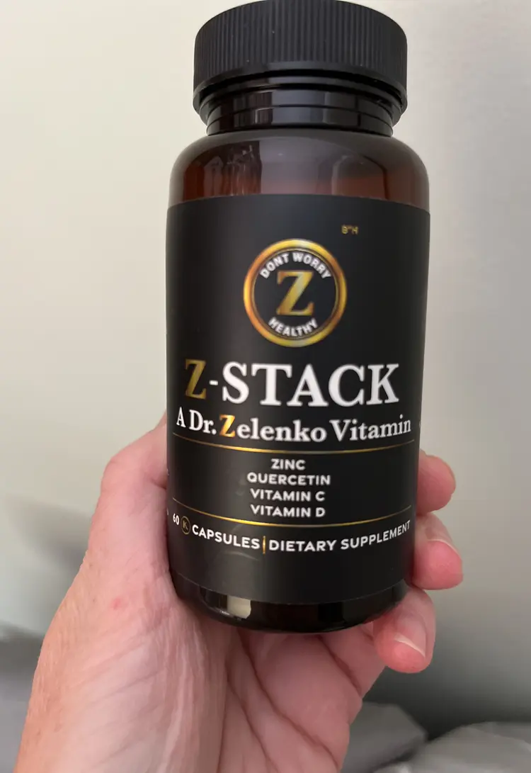 Hand holding a bottle of Z-Stack dietary supplement.