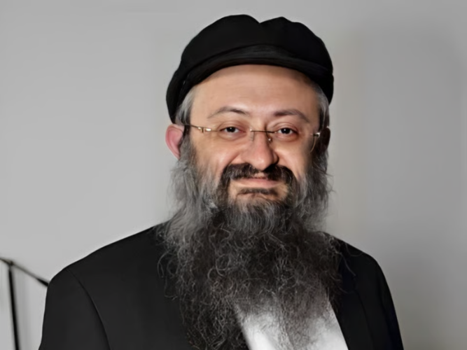 Man with a beard and glasses wearing a black hat and suit.