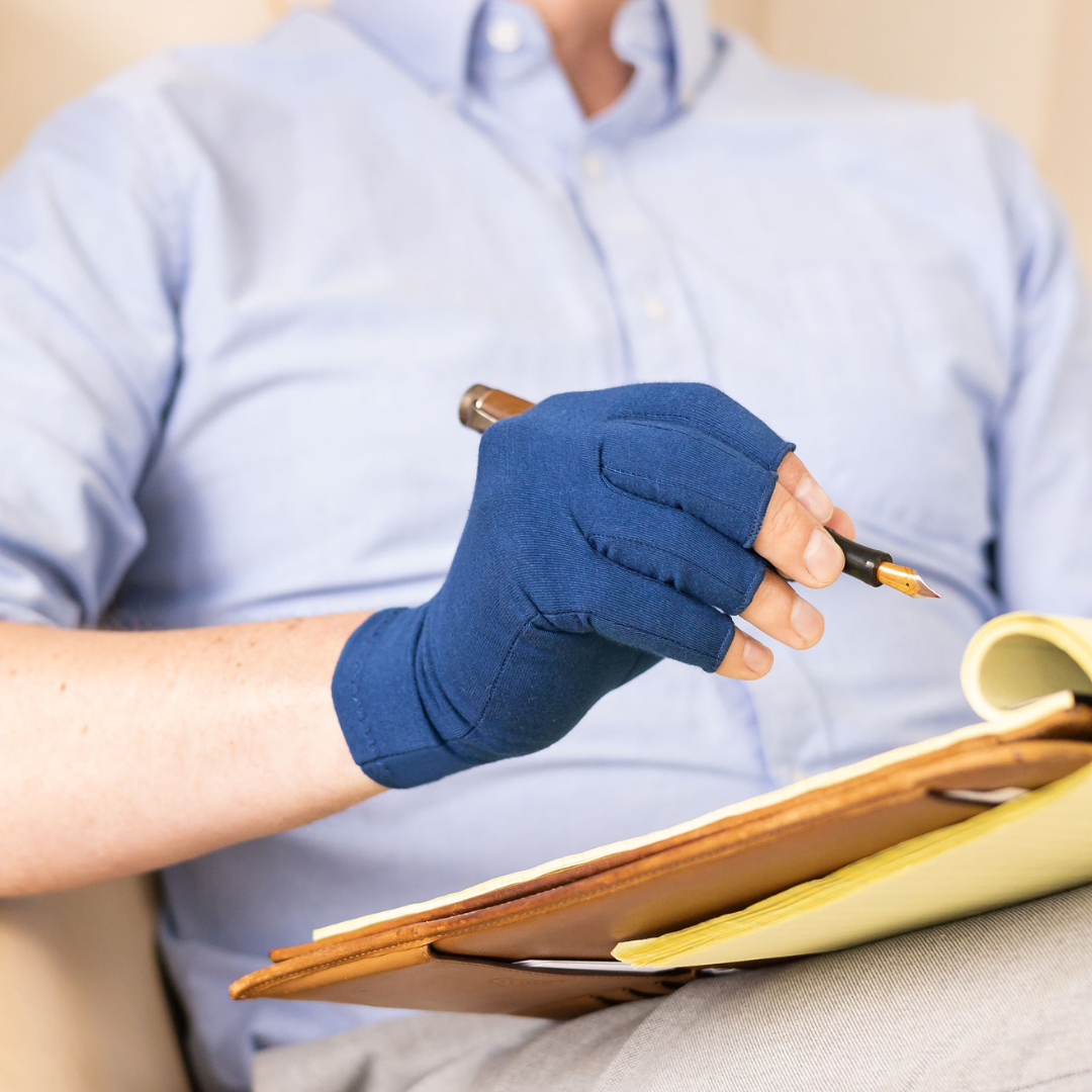 Person wearing blue compression gloves writing on a notepad.