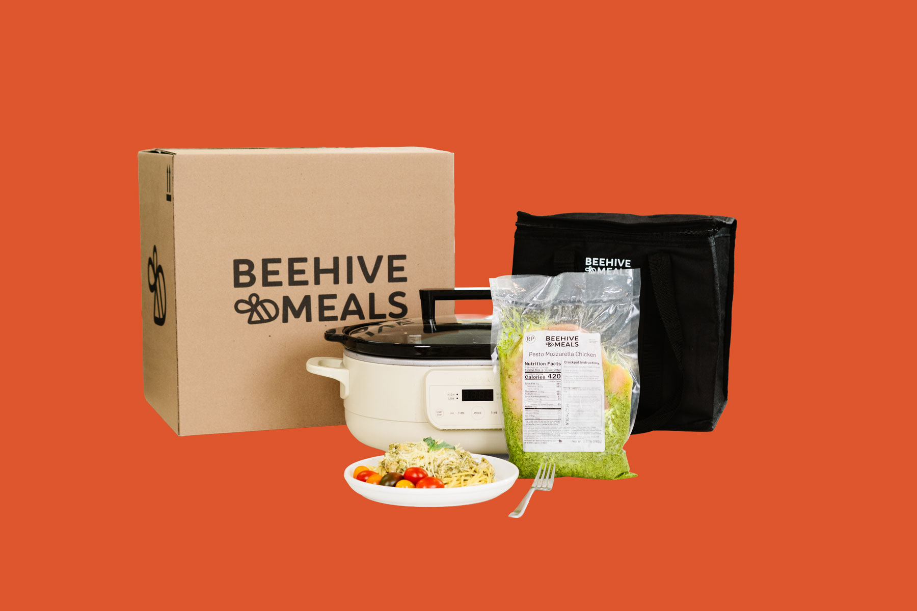 A Beehive Meals delivery kit including a box, slow cooker, packaged ingredients, and a prepared pasta dish.