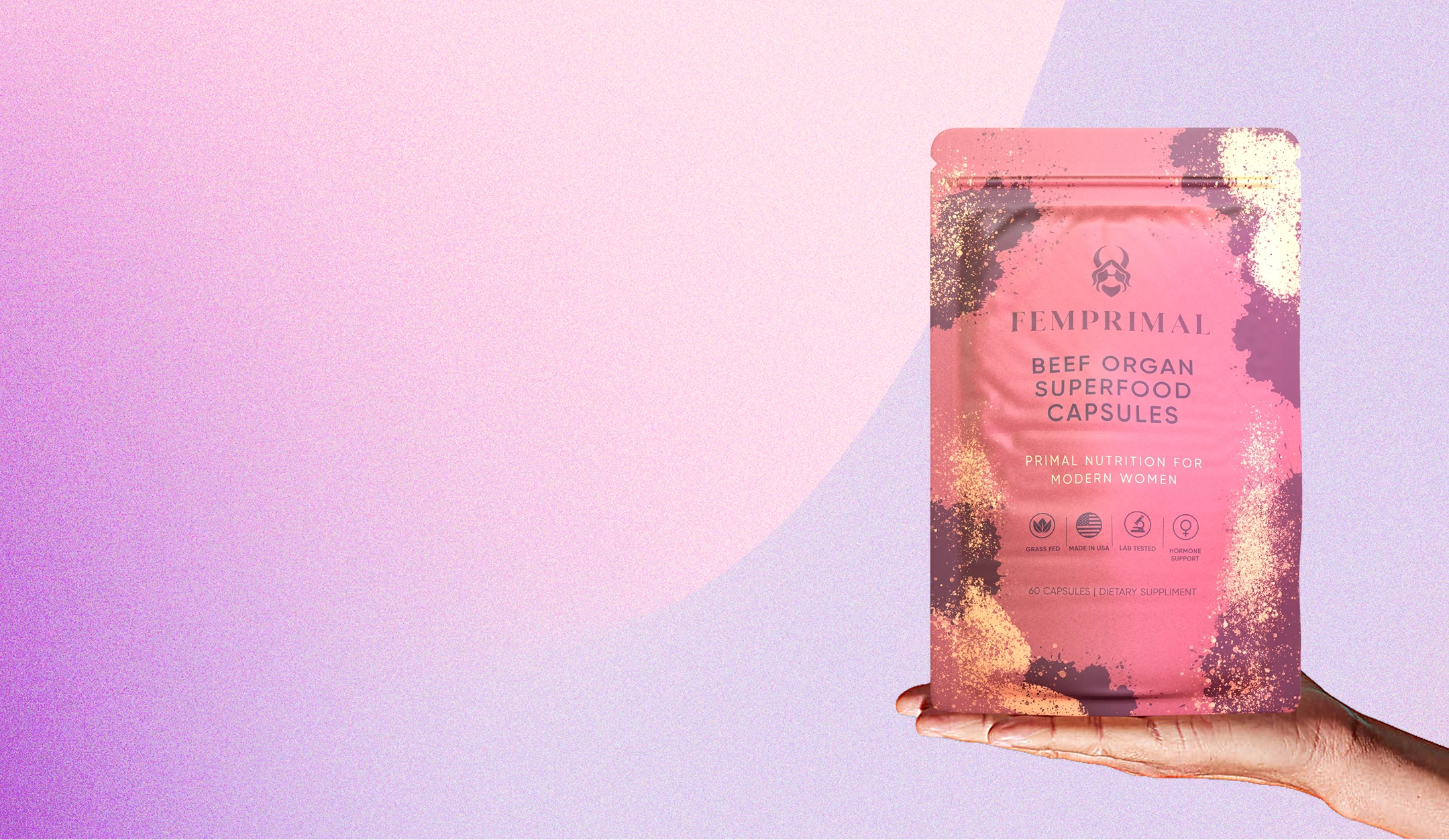 Hand holding a pink package of beef organ superfood capsules.