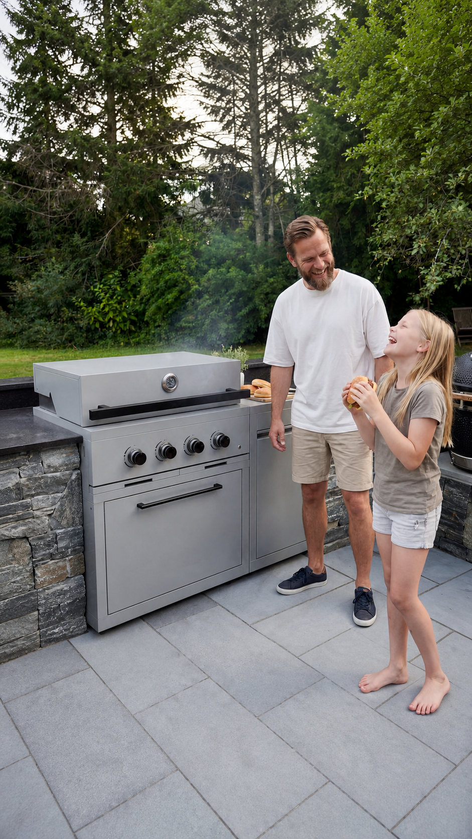 A father and daughter laugh together by an outdoor grill on a patio, the daughter holding a burger.