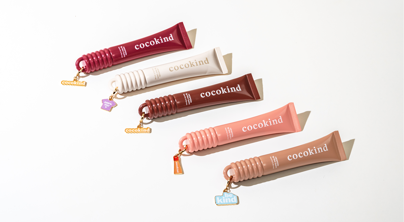 Five colorful tubes of skincare products with keychain charms.