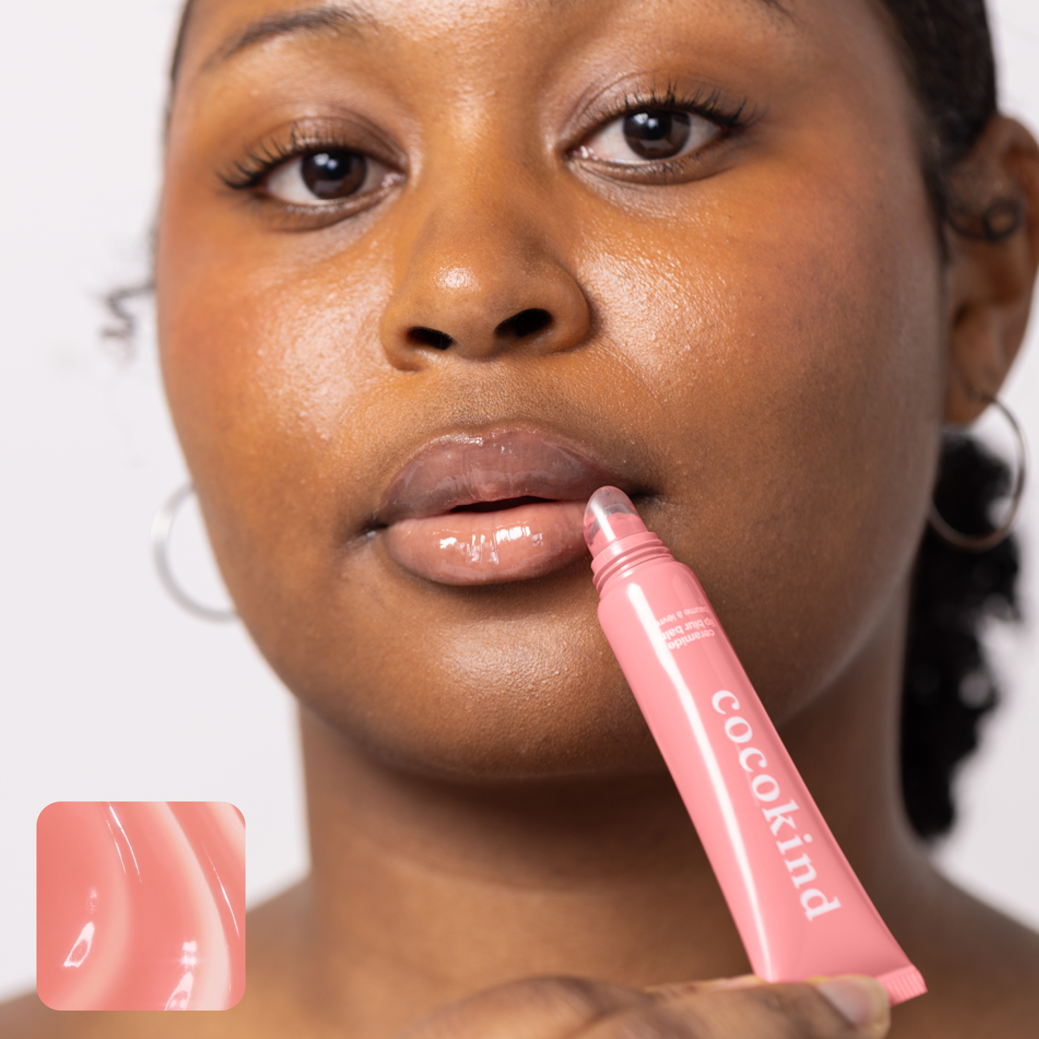 Person applying Cocokind lip gloss from a pink tube.