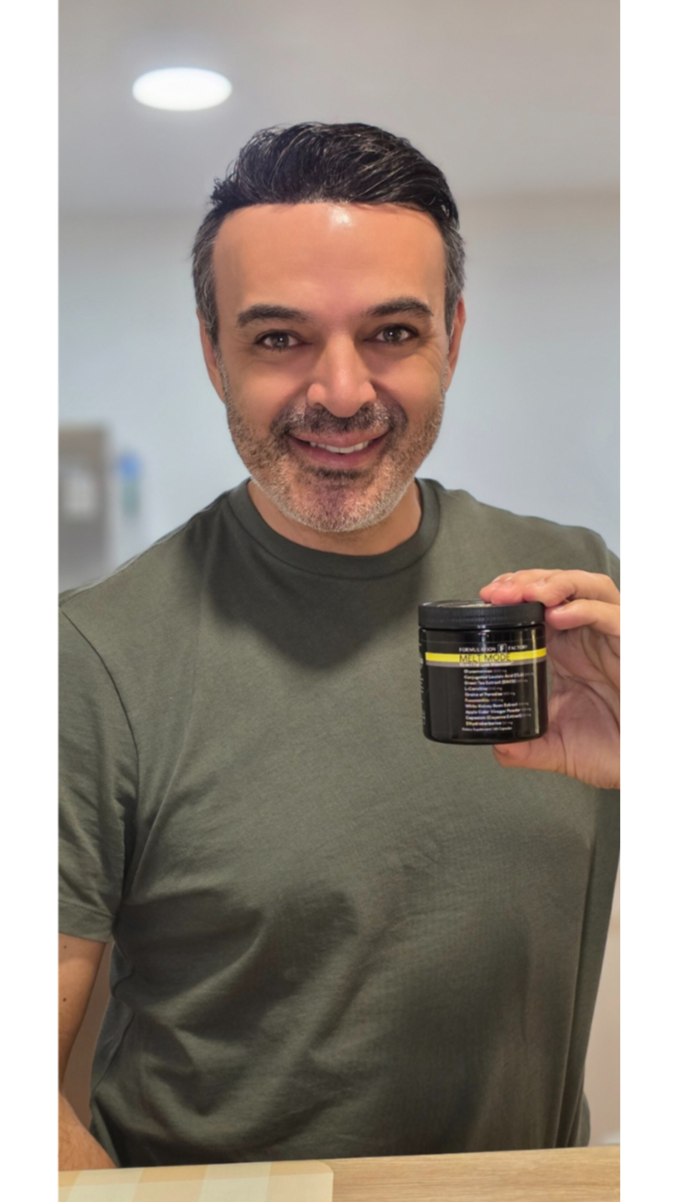 Person smiling and holding a black jar with yellow label.