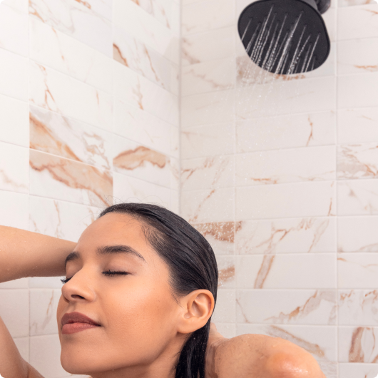Person enjoying a shower with water flowing from a showerhead.