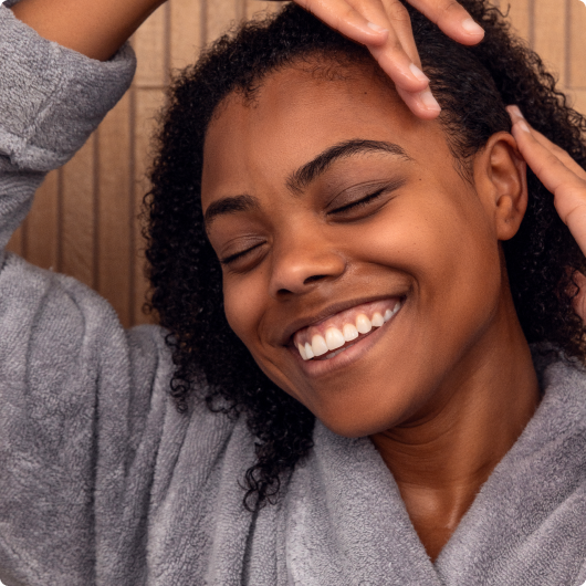 Smiling person in a gray robe with relaxed, joyful expression.