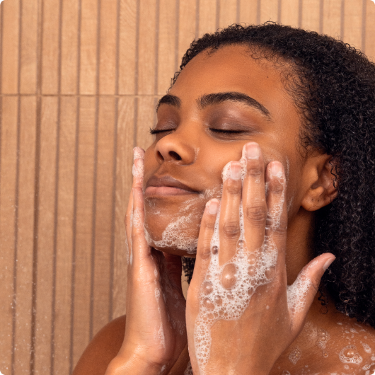 Person washing face with soap in a serene expression.