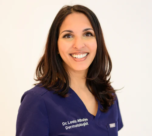 Headshot of Dr. Leela Athalye, a dermatologist, smiling in blue scrubs against a white background.