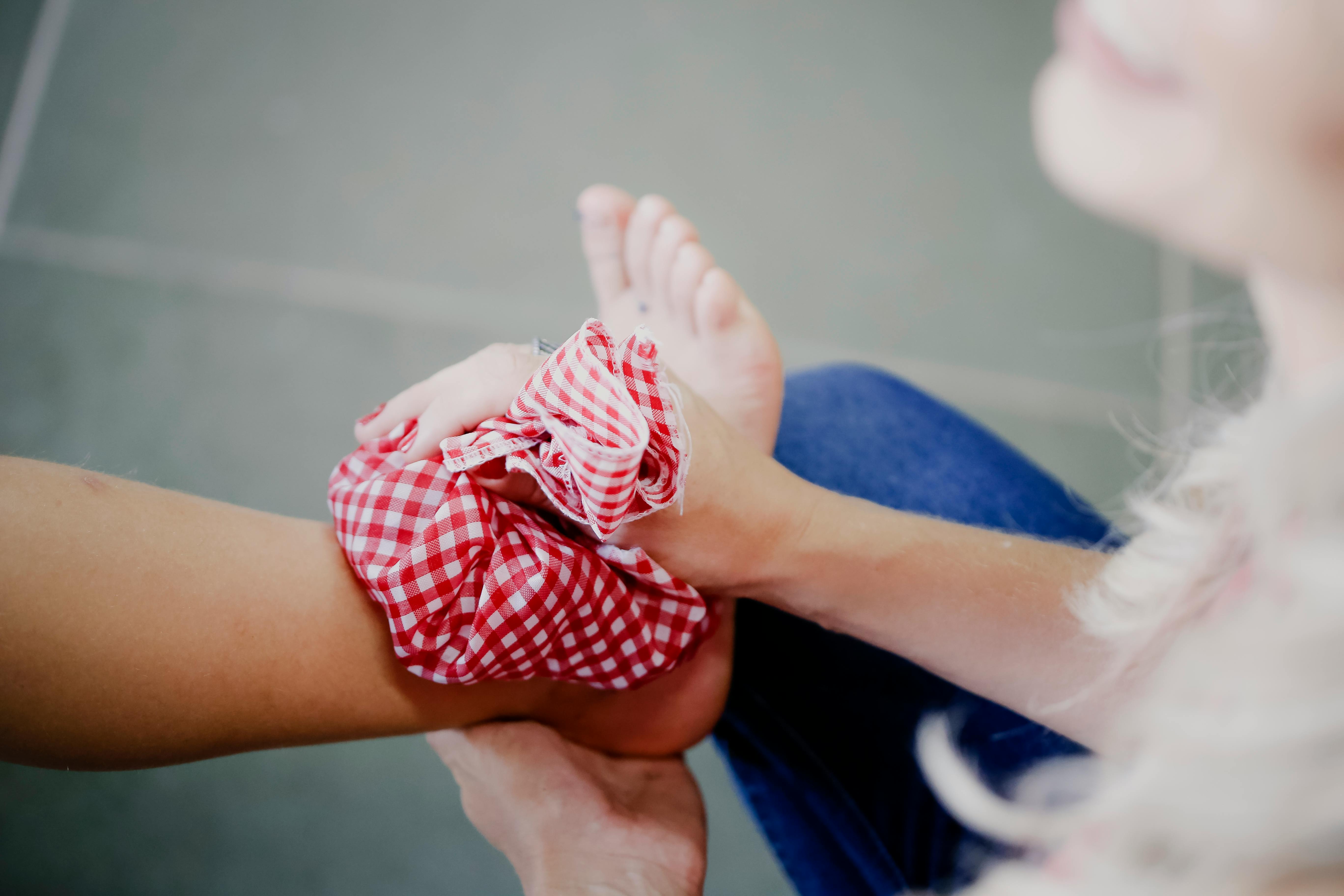 Person applying a red checkered cloth to a foot.