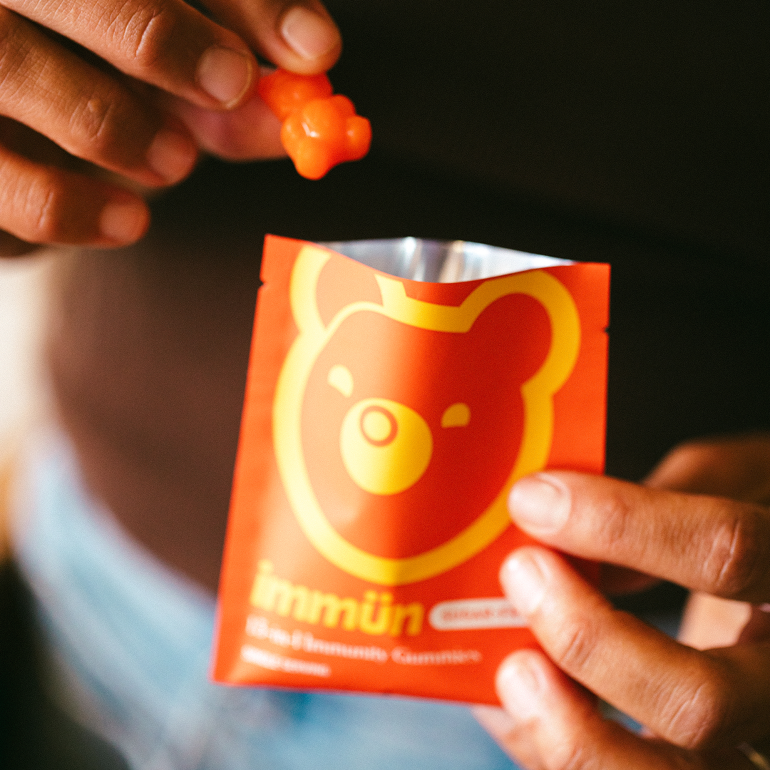 Person holding a packet with a bear logo, taking out a gummy bear.