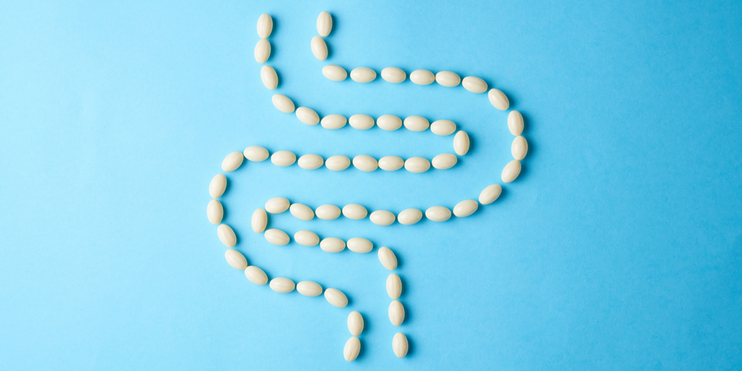 White pills arranged in the shape of intestines on a blue background.