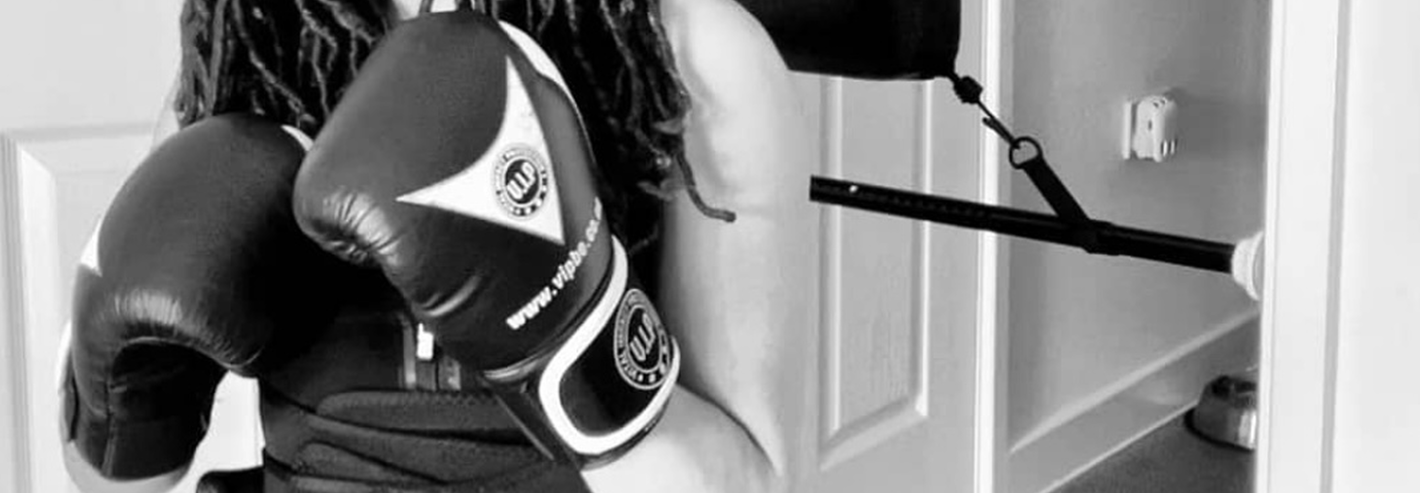 Person wearing boxing gloves using a resistance band attached to a door.